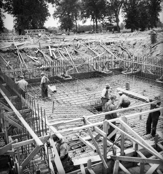 Elevated view of construction workers placing rebar in the foundation of a house in preparation for concrete to be poured.