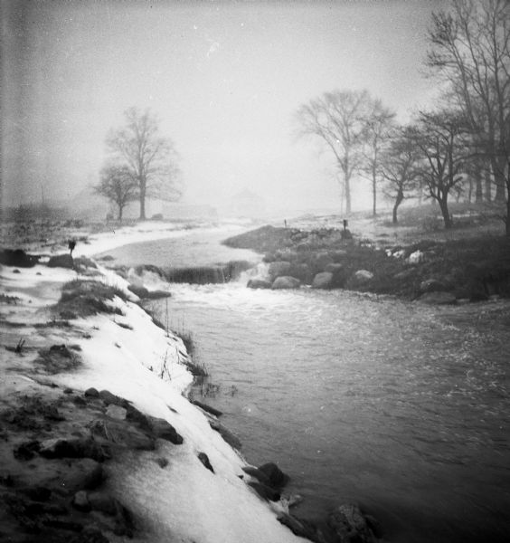 The Root River swollen with rainwater and/or snow melt. This picture was likely taken as a study of the water drainage in early Greendale.