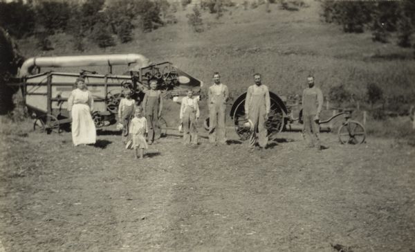 A family in front of a La Crosse Happy Farmer tractor hitched to a threshing machine.