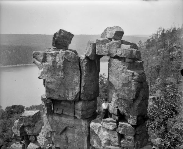 Elevated view of a woman standing in the Devil's Doorway above Devil's Lake. There is graffiti on the rocks.