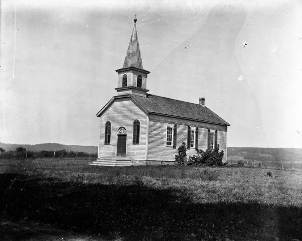 Exterior view of the Harrisburg Church. There are long hills in the background.