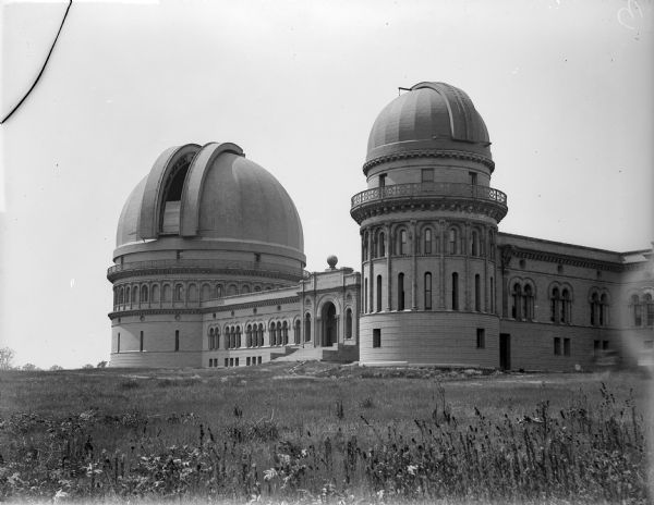 Exterior view of Yerkes Observatory showing the entrance and two domes. There are prairie plants in the foreground.