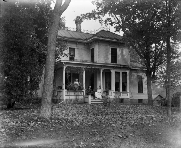 Exterior view of the Monroe (Munroe?) House, with three people posing on the front porch.