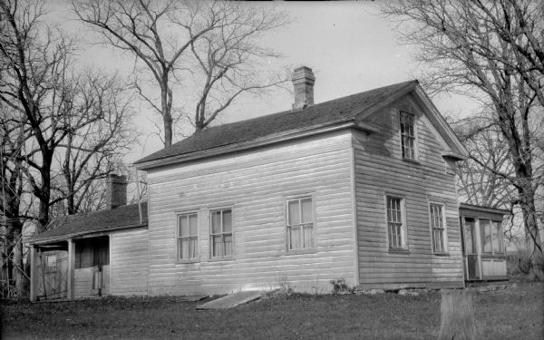View of the Low Tavern from the yard. There are two small porches on the left and right side of the building, and two chimneys.