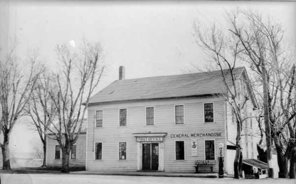 A large, two-story wood building with nine over six windows identified as an inn; at the time of the photograph it served as the Butte des Morts Post Office, a general store and gas station.