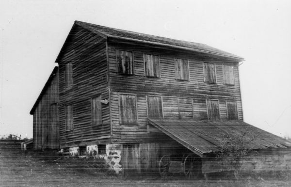 This two-story wooden structure was originally the house of LaFayette Hill (1812-1853), a member of Wisconsin's first Constitutional Convention and settler of Dekorra. The windows are boarded up, and a wagon is stored under a lean-to attached to the building.