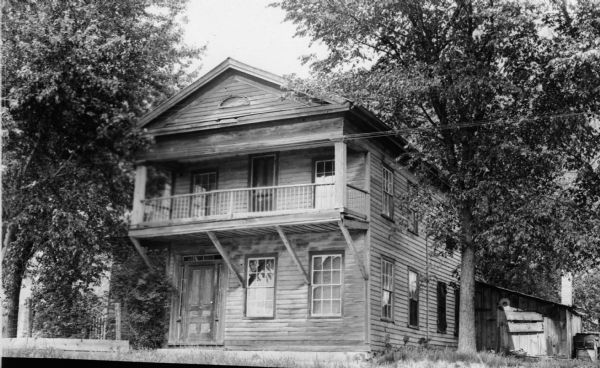 The 1847 Ferry House, a two-story wooden, classical revival style structure with six over six windows. There is a second-story front porch and small lean-to on the side.