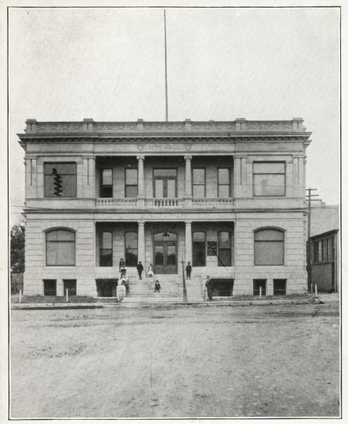 Exterior view of the front entrance of the Appleton Free Public Library and City Hall. Several children are posing on the entrance steps. The City and the Y.M.C.A. funded the library with $40,000. Note above picture reads, "Appleton."