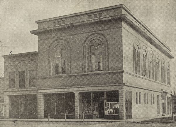 Exterior view of the Elkhorn Public Library and a larger, two-story, brick building, with a storefront on the first floor. The Elkhorn Public Library is the smaller, two-story brick building with a pencil "X" near the door and an ink "X" over the roof. On the mounting it reads: "Elkhorn upper floor and X entrance to library."