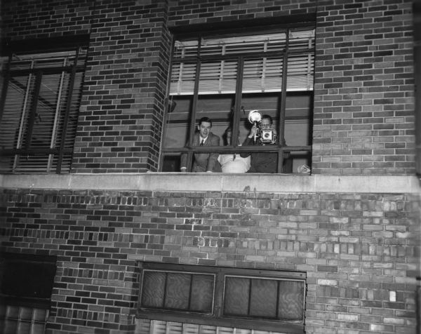 James Newman, public relations director of the Rath packing company, takes photographs of striking workers from a window of the company's factory.