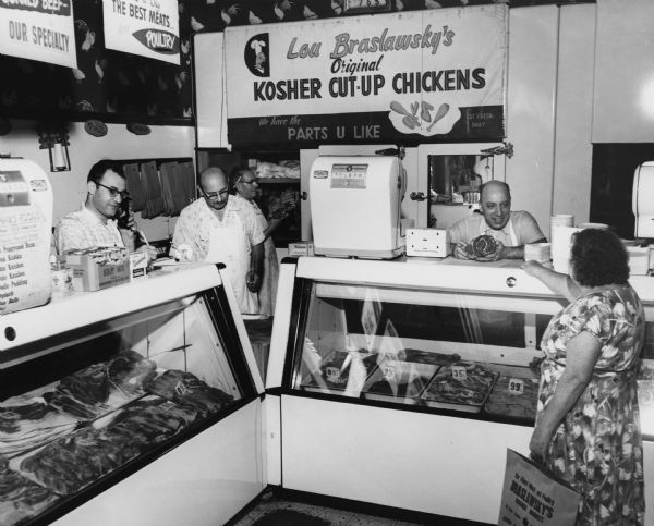 At Lou Braslawsky's kosher meat market, a butcher holds a roast for a customer to examine. A sign at the back of the store suggests that chickens, not beef, was the market's specialty. The kosher butchers were members of the Amalgamated Meat Cutters union.