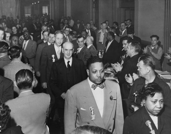Philip Murray (dark suit in the center of the photo), the president of the CIO, being escorted to the podium to speak to the annual convention of the United Packinghouse Workers Union, a CIO union.