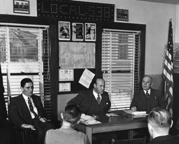 Nathan G. Feinsinger (center), professor of law at the University of Wisconsin and a nationally-known arbitrator of labor disputes, with two Wisconsin colleagues, George Bohacek (left) and Harry S. Sutherland.  The three men are in the Madison headquarters of the Amalgamated Meatcutters and Butcher Workers Local 538.