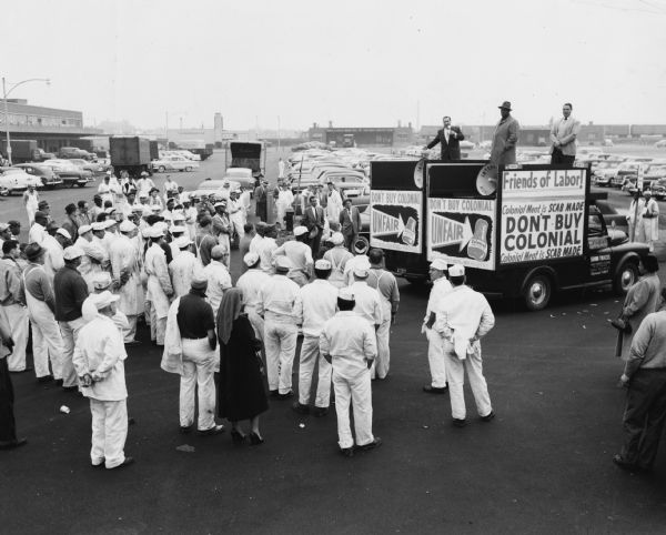 In this uncaptioned photograph from their archives, members of the United Packinghouse Workers union are seen standing on two sound trucks speaking to the employees of a company that was not on strike.