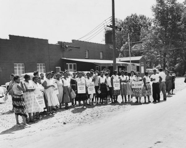 Women workers on strike against the Holly Farms Poultry Company, posed outside for a "solidarity" picture. Dorothy Johnson, wearing the third picket sign from the left, was the head of the strike committee.