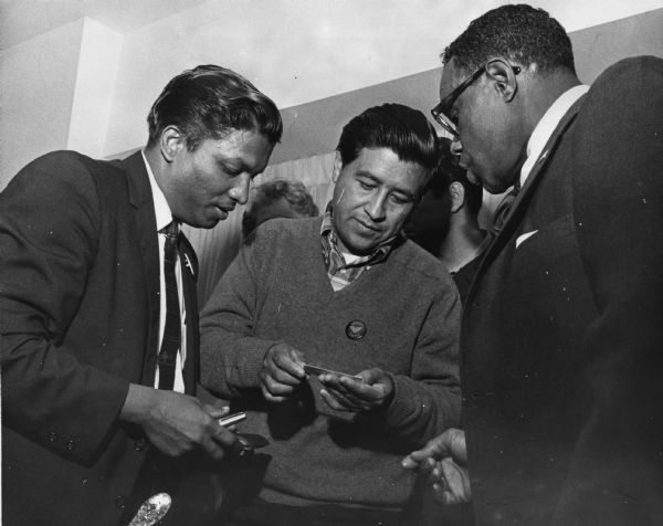 Cesar Chavez (center) head of the Farm Workers Organizing Committee, receives a Ghandi commemorative medal from Theodore Mazarello (left) of the Gandhi Centennial Committee of Chicago. Hilton Hanna, an officer of the Amalgamated Meat Cutters and Butcher Workers union and a board members of the Gandhi committee, looks on.