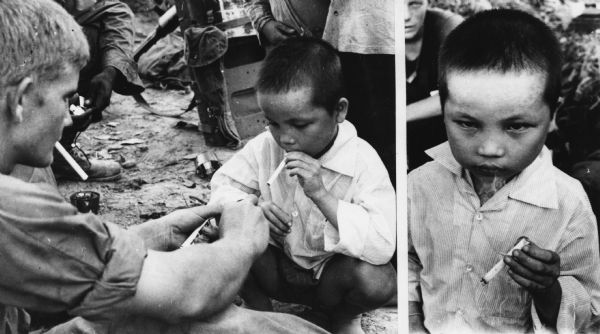 At Thuong Duc, South Vietnam, a U.S. Marine and a Vietnamese youth share a cigarette break. The UPI caption indicated that the boy acted as if he had been smoking for years. The photographer for UPI was Shunsuke Akatsuka.