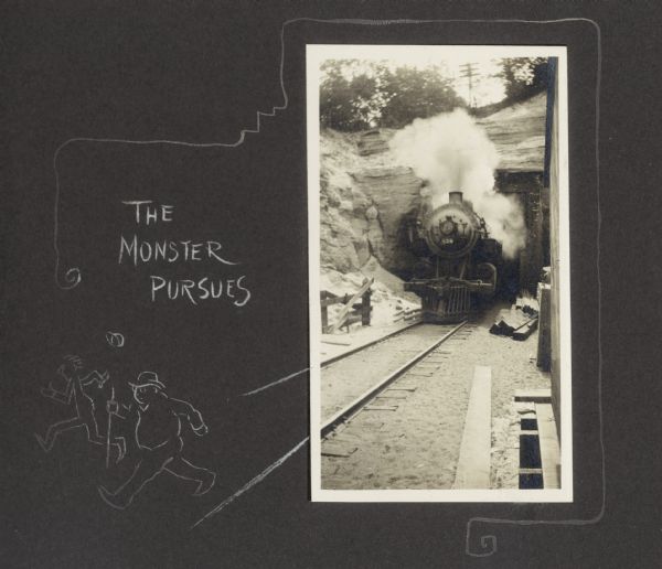 Front view of train emerging from a tunnel. A hand-drawn border features two male figures running away from the train and reads, "The monster pursues."