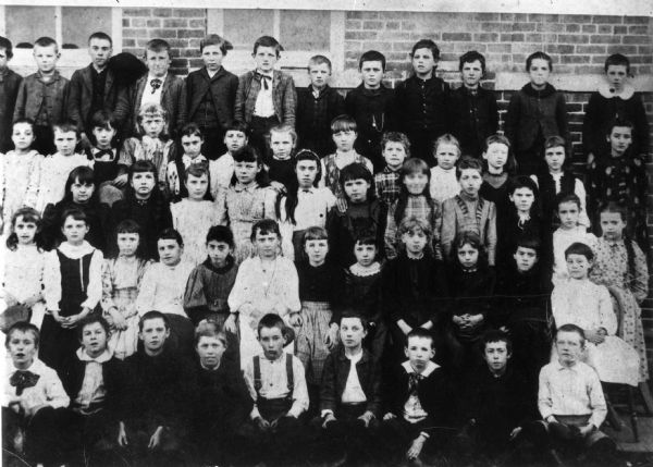 A group portrait of students of the Wisconsin School posing outdoors. Frank O. King is second from right, in the front row.