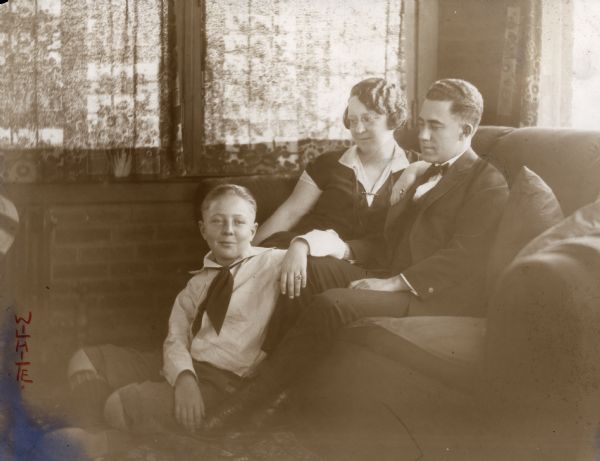 A family portrait of Robert Drew King, seated on the floor, and Delia Drew King and Frank O. King sitting on a couch.