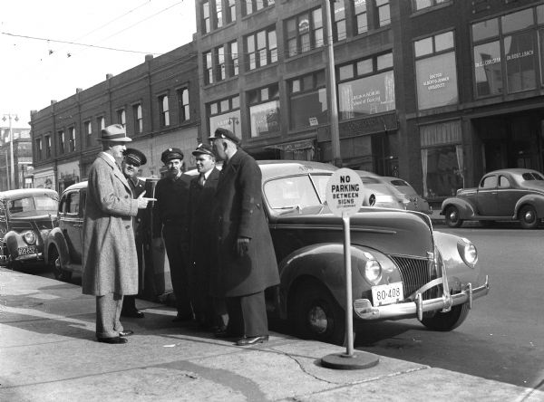 Carl Zeidler speaking with cab driver (i.e. the working man) for a campaign brochure. Three other men are standing with them on the curb.
