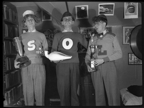 Humorous photograph of Koplin, Bloch, and Gauer dressed as college boys wearing letter sweaters that spell out SOL, for shit-outta-luck. Gauer states they felt like they had no future because of jobs and the depression. Koplin went on to direct the $64,000 Question and ran into trouble associated with that show.