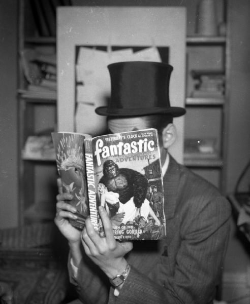 Bloch wearing a top hat and reading one of his published stories in <i>Fantastic</i> magazine. This is not a Gauer photograph, but a copy of a negative of a picture of Bloch taken by one of his fans, Dean Grenelle, in Green Bay, Wisconsin.