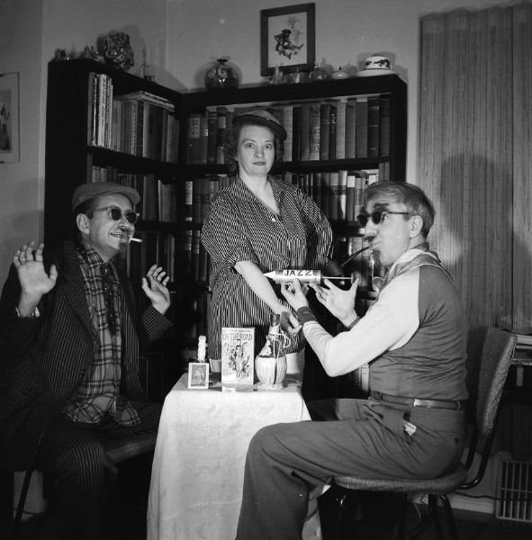 Amusing portrait of the gang "spoofing" jazz and beatnik culture. Alice Bedard is receiving a hypo injection labeled "JAZZ" from harold Gauer while Robert Bloch observies. They are posing in the Lake Drive apartment.
