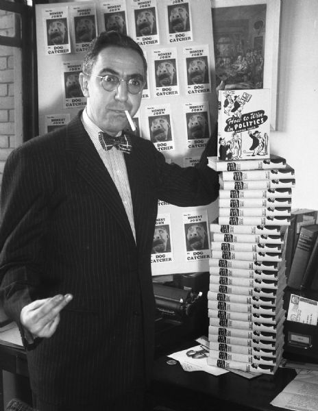 Gauer "promo" photograph taken with a stack of his just published book: "How to Win in Politics," outlining Robert Bloch and Harold Gauer's modern campaign strategies. Photograph was taken in Milt Polland's office.