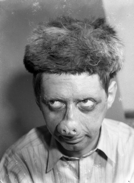 Author Robert Bloch wearing a prosthetic pig-like nose, wig, and makeup.