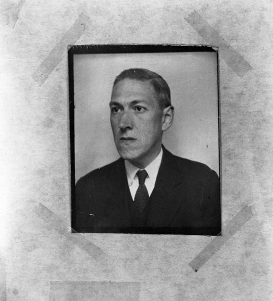 Head and shoulders portrait of H.P. Lovecraft wearing a suit jacket, vest, and tie taped to a piece of paper.