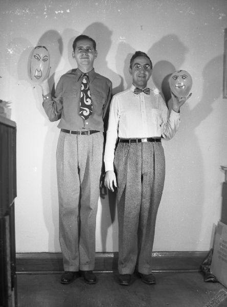 Robert Bloch and Harold Gauer posing indoors, making goofy faces while they hold balloons with faces drawn on them.