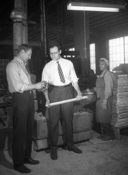 A campaign picture of Democrat Henry Reuss with his sleeves rolled up in a factory talking to a foreman while an African-American worker looks on. This was likely taken in 1952 while Reuss was running against then-Senator Joe McCarthy.