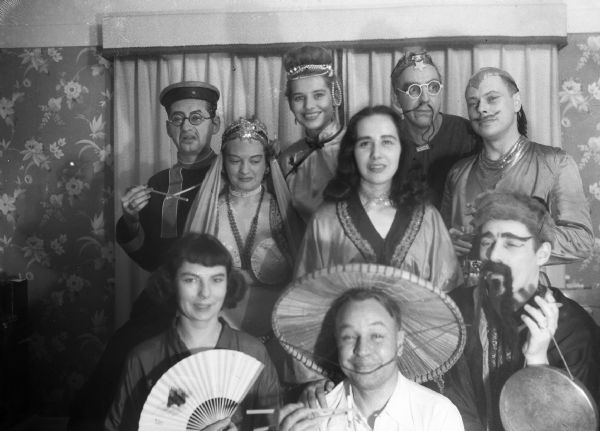A group of people wearing Asian costumes of "Oriental stereotypes." In the back row from left to right are Robert Bloch, Alice Bedard, Angie Vail, Mary Jo Vonier, Harold Gauer and Bob Vail. In the front row on teh far right is Sprague Vonier. The other two people are unidentified.