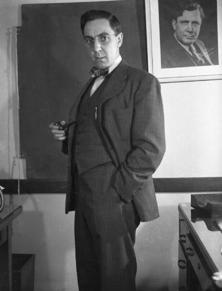 A self-portrait of Harold Gauer standing holding a pipe and wearing a jacket, vest, and bow tie.