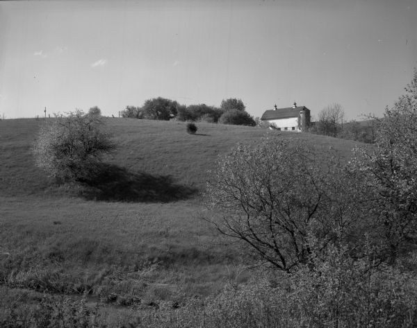 Landscape view up hill of the James R. Lloyd farm. A dairying barn is visible on the top of the hill.