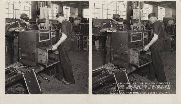 Two workers at the Malleable Iron Range Company begin assembling a stove. Caption on stereograph reads, "No. 13 The beginning of the building process. The body held rigid and true on a specially constructed table, while inserting the oven. Malleable Iron Range Co, Beaver Dam, Wis."