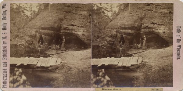 Four women gather in the Diamond Grotto, a notable land form in the Wisconsin Dells. There is a rustic bridge in the foreground.