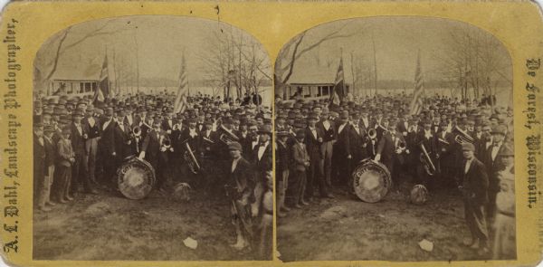 A large group, mainly men, are gathered behind the "Lake City Cornet Band" who are in uniform near a lake shore, possibly Lake Monona. The card was marked "17th of May, Madison, Wisconsin." This date and the presence of the Norwegian flag clearly means that this was the Syttende Mai (May Celebrations).