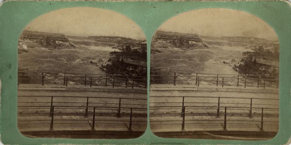 Elevated view of St. Anthony's Fall. Caption on back of stereograph reads, "St. Anthony's Falls, Minneapolis, Minn." There is a bridge in the foreground, and buildings are on both sides of the falls.