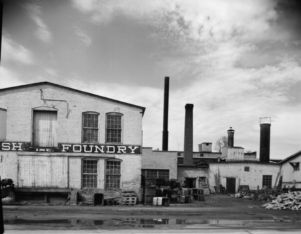 An industrial scene of a foundry with piles of material in a side yard.