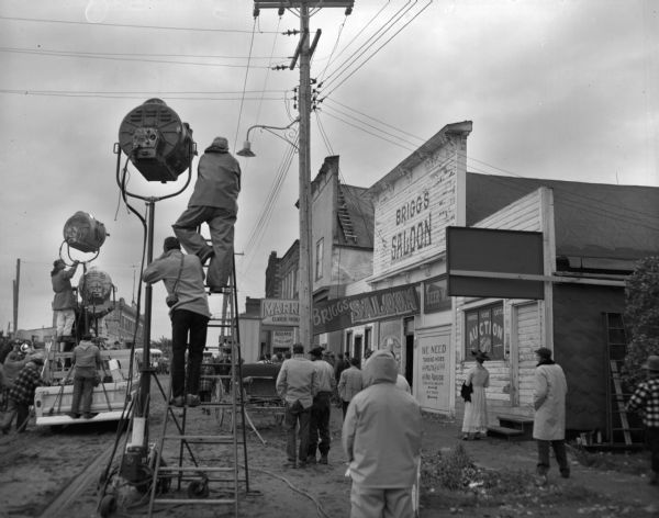 Caption on negative jacket reads, "The 20th Century Fox motion picture studio crew at work filming 'Hemingway's Adventures of a Young Man,'  based on Ernest Hemingway's published stories of his youth in the Saxon area in 1916. The town was altered and painted to serve as a set."