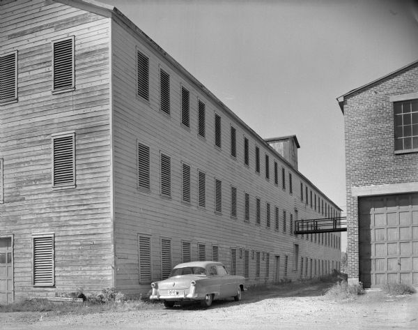 View of the Blum Brothers Company factory building. The Blum Brothers Company once manufactured circular cheese boxes. An automobile is parked outside the factory building.