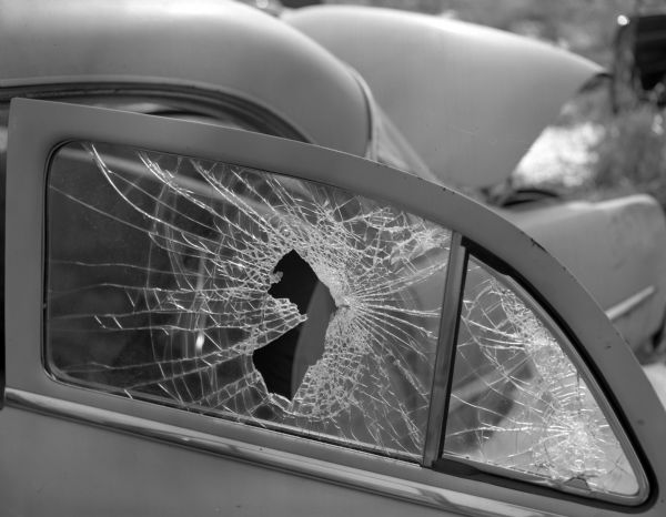 View of a wrecked car with a broken car door window in Chief's automobile junkyard.