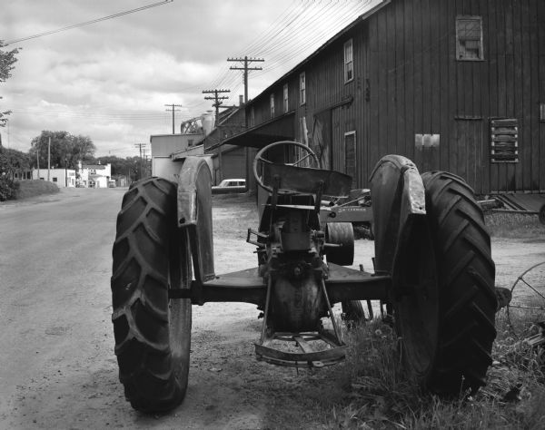 A parked tractor on a street near industrial buildings.