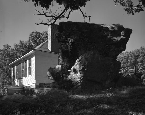 Exterior view of a school house near Highway F. A large rock outcropping resides in the schoolyard.