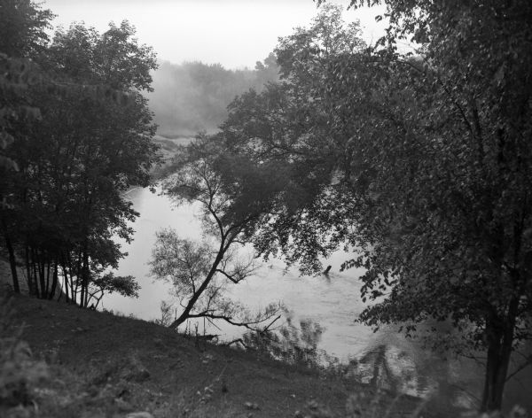 A tree-lined view of the Wisconsin River. The photograph was taken from an elevated area near a highway.