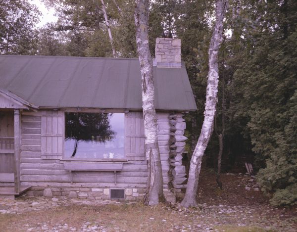 A close view of Jack Myers' log cabin on Washington Island. The cabin is surrounded by thick woods.