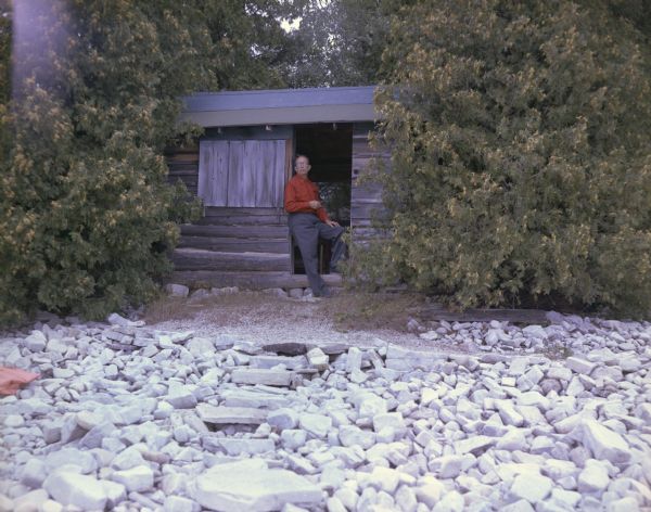 Lloyd Lehman stands in the open doorway of his small cabin on Washington Island. This cabin is one of a number of former summer camp buildings.