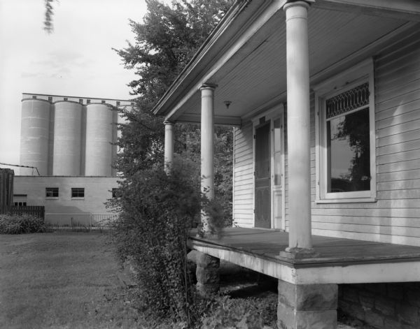 View of the porch of a vacant at 535 10th Avenue with grain elevators in the background. This particular group of grain elevators were called "Tanktown."